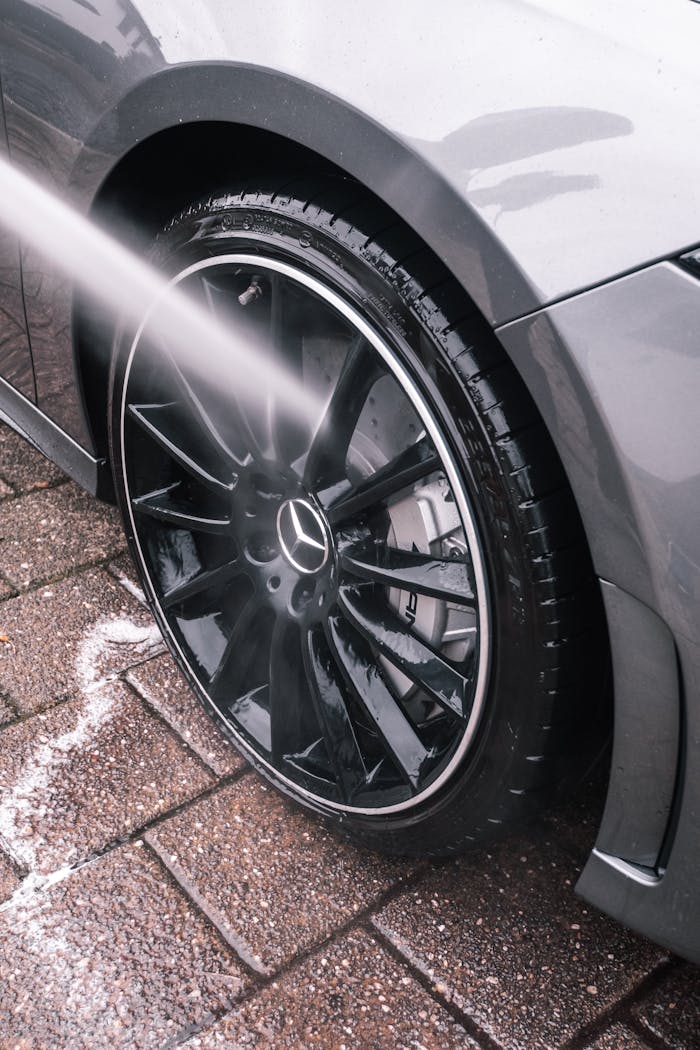Detailed shot of a car wheel being washed with water on a brick sidewalk.